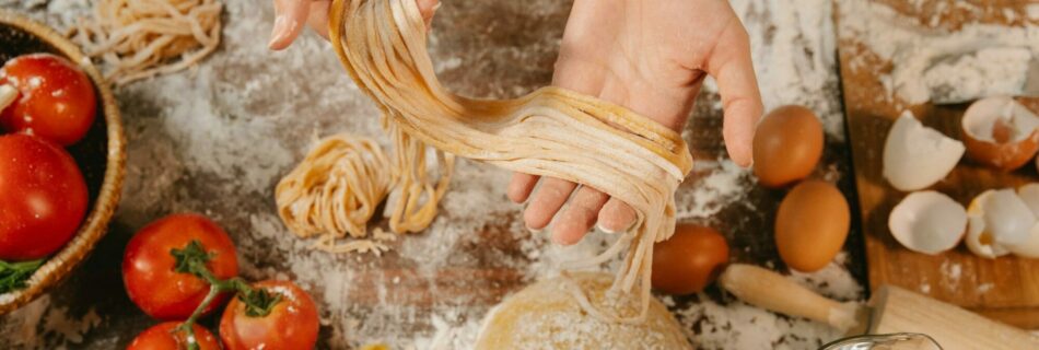 Bild von frischer Pasta, die gerade gemacht wurde und in den Händen gehalten wird.